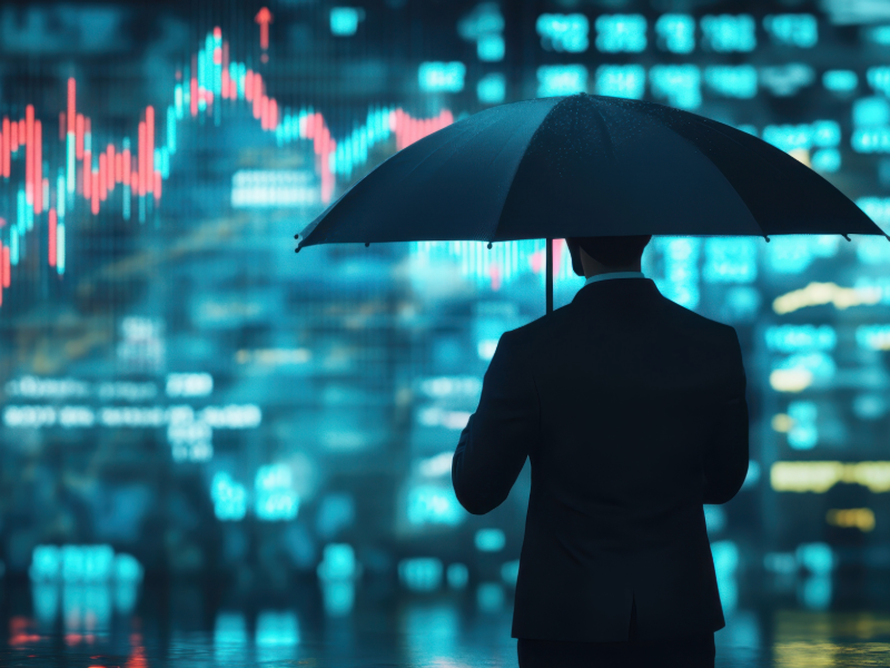 Businessman with umbrella looks at stock market activity on a screen